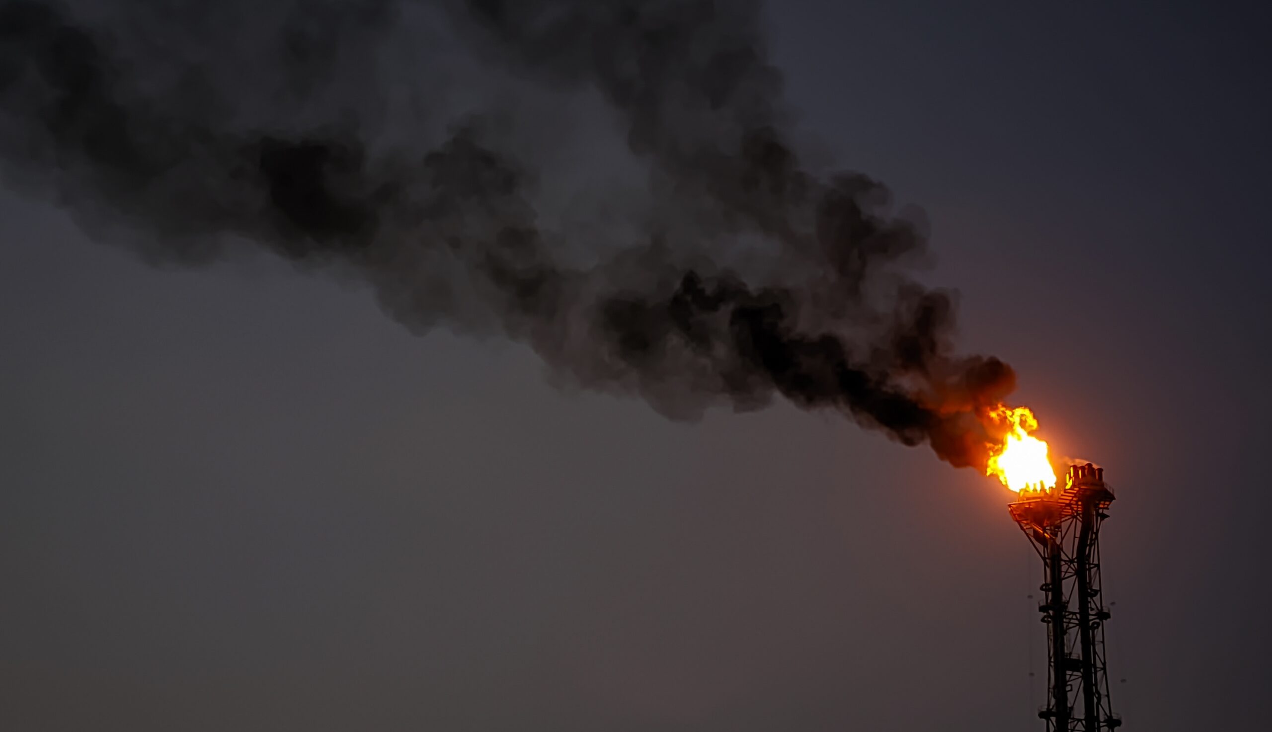May contain a tall industrial flare stack emitting flames and black smoke against a dark sky.