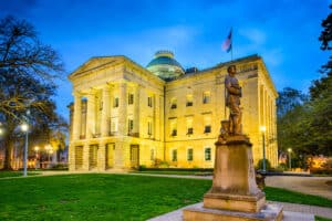 May contain a statue of a person in front of a lit neoclassical building.