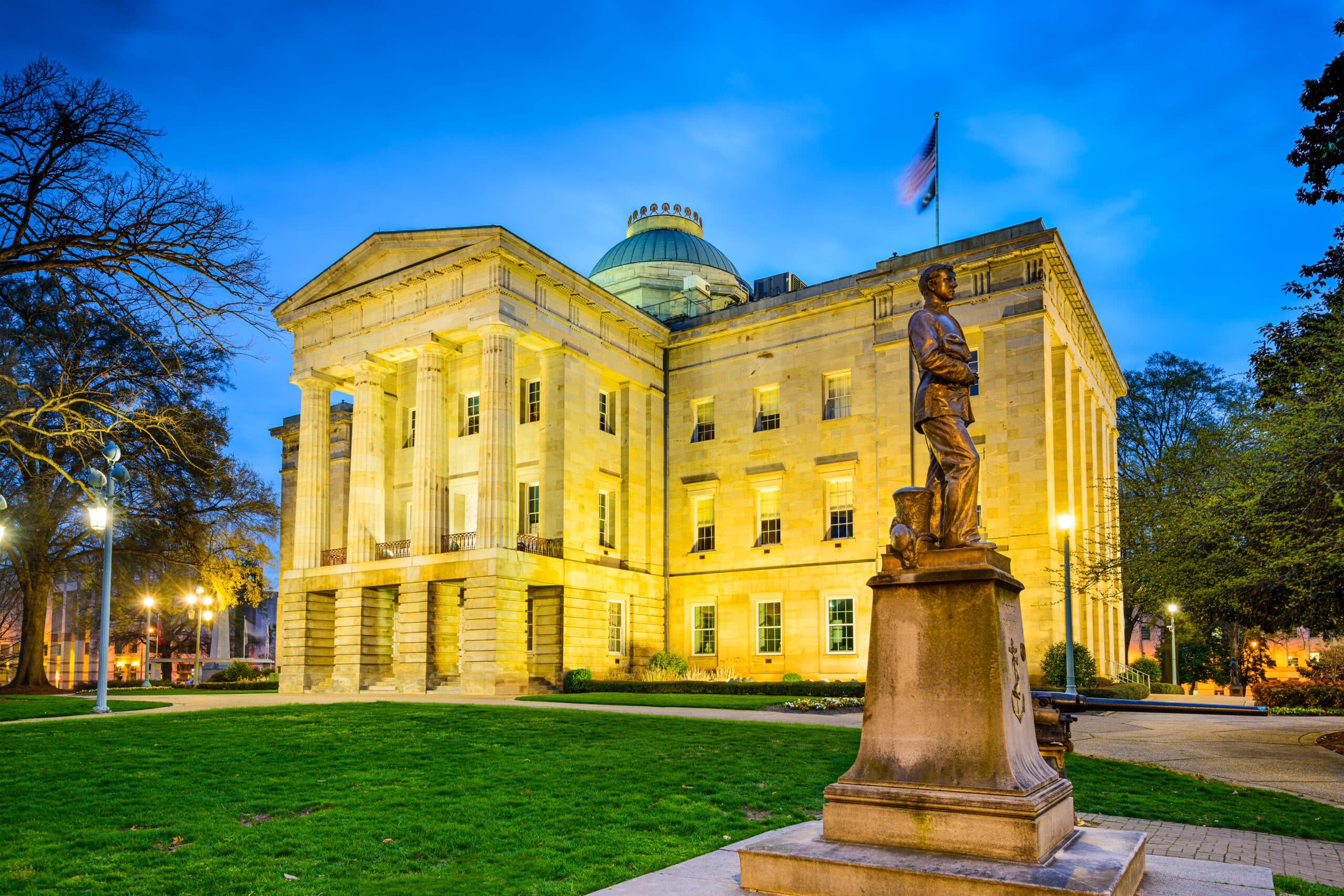 May contain a statue of a person in front of a lit neoclassical building.