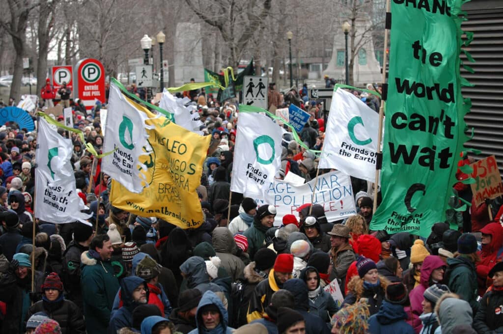 May contain a crowd of people holding flags, one reads "the world can't wait".