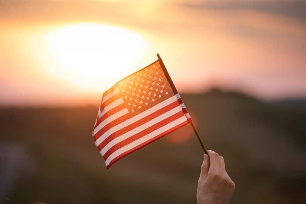 May contain a person holding an American flag at sunset.