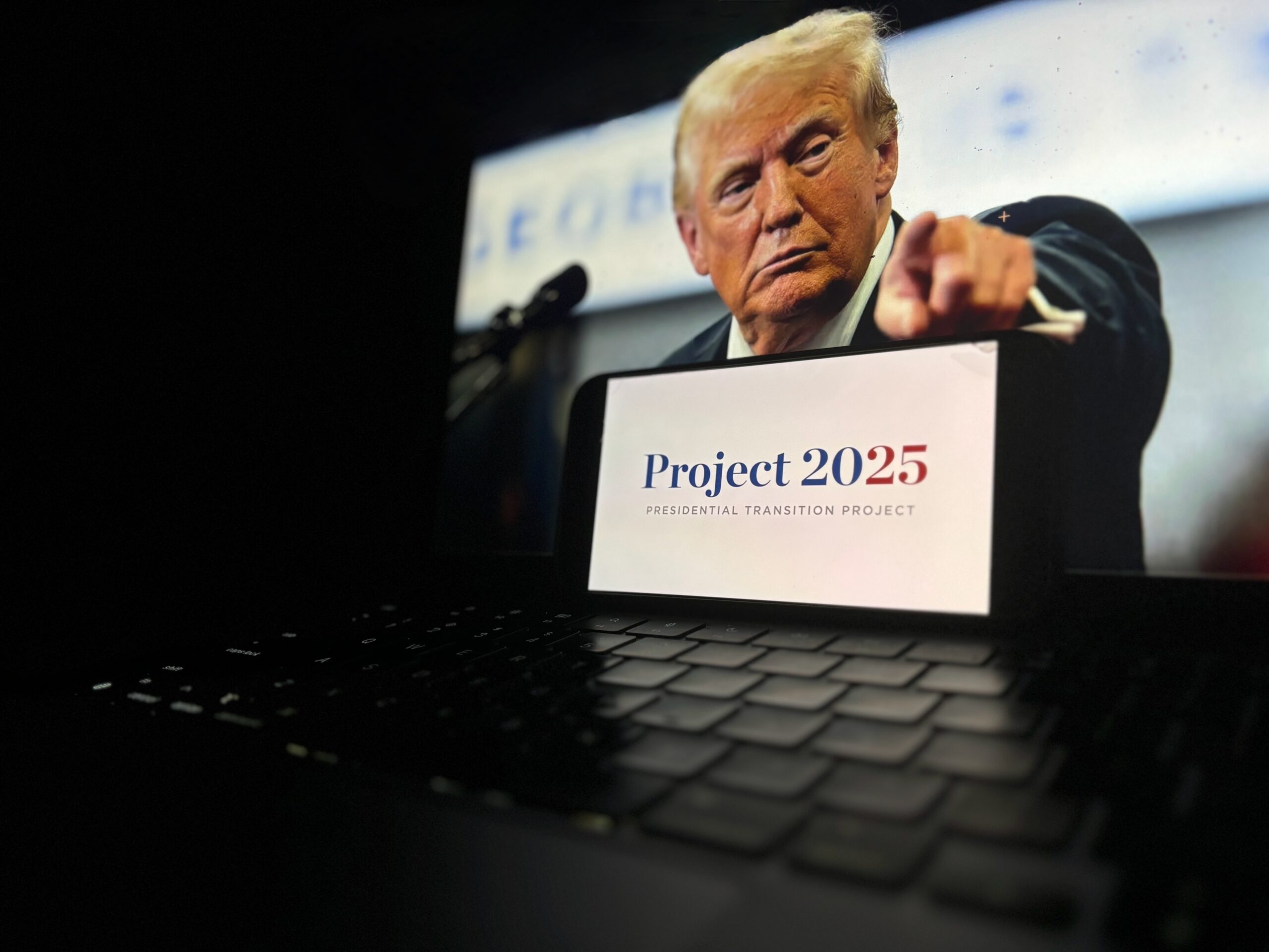 May contain one person pointing at the camera with a smartphone displaying "Project 2025".