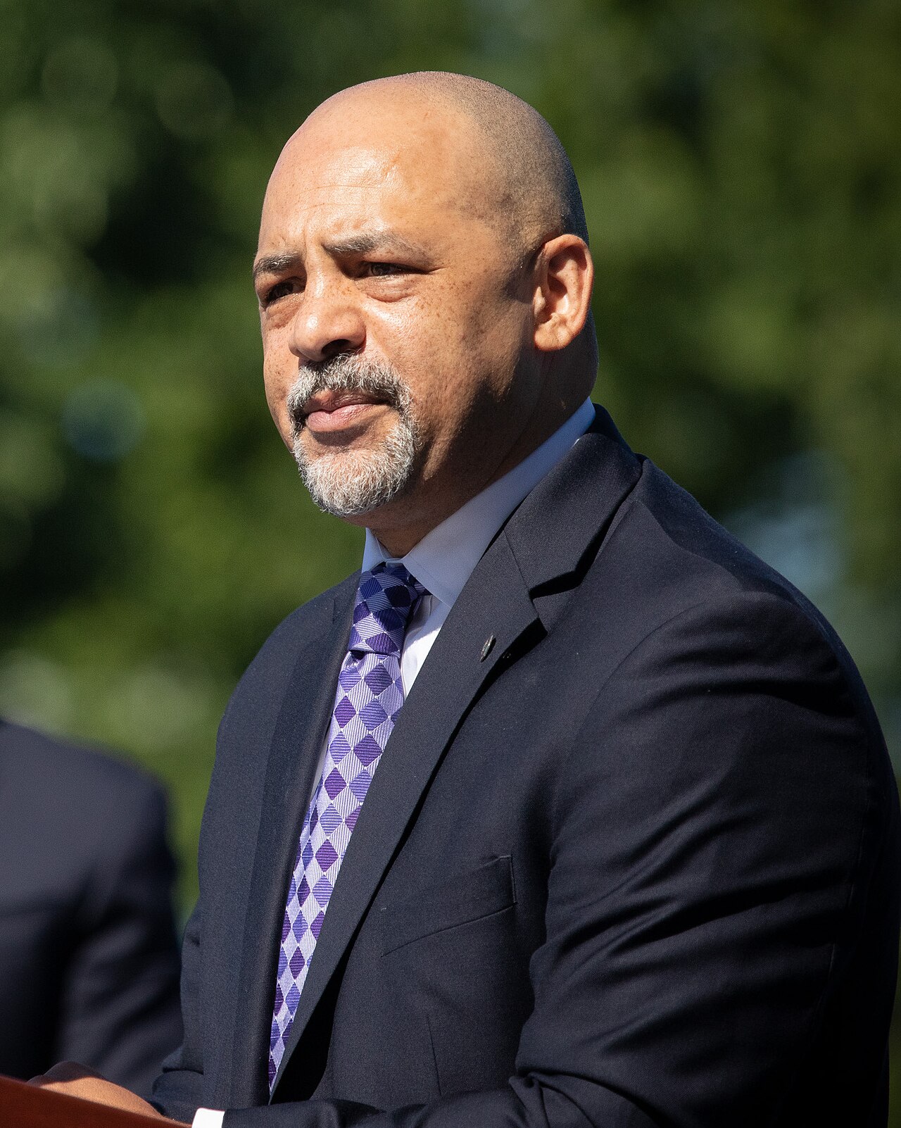 May contain one person wearing a suit and a purple tie outdoors.