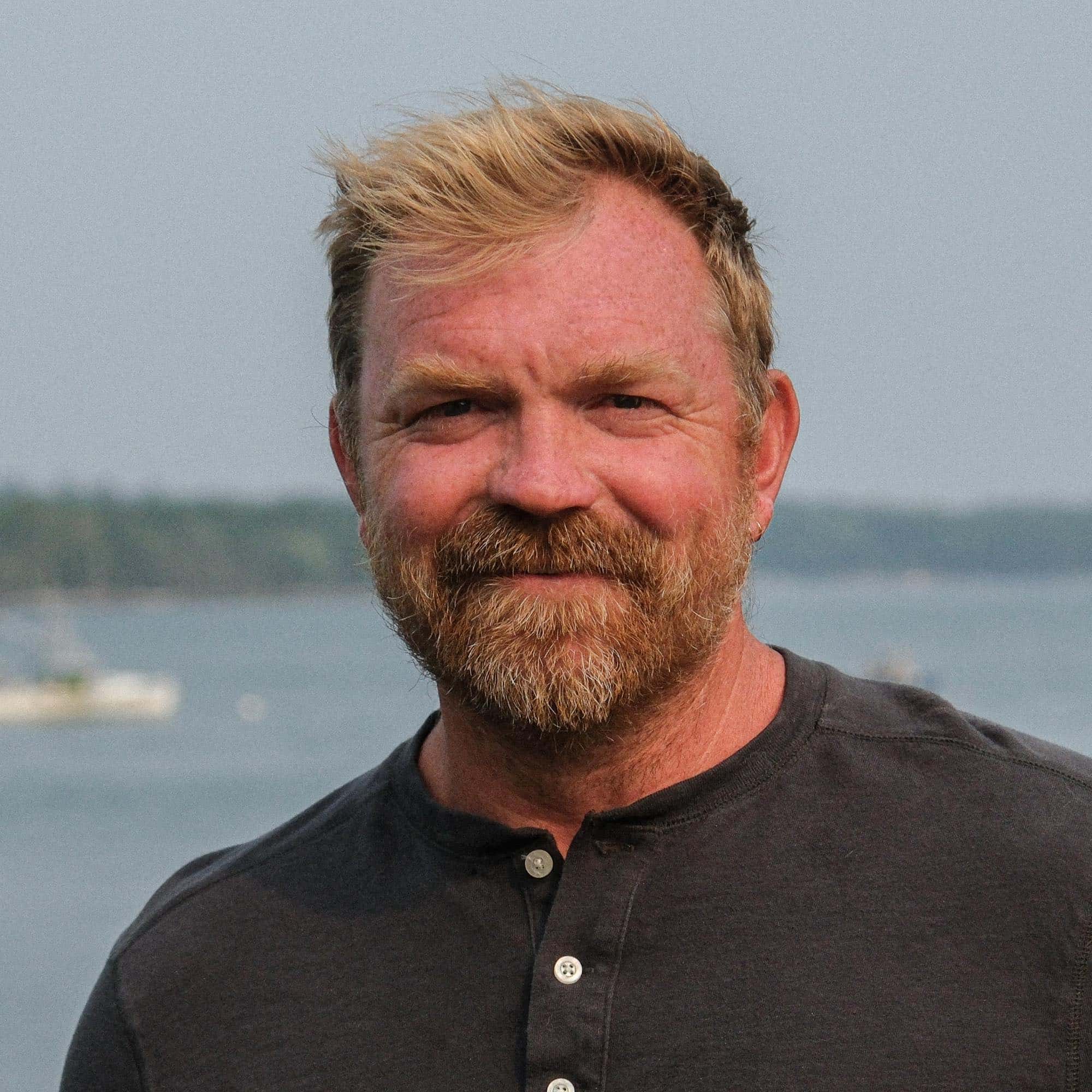 May contain a person with blond hair and beard wearing a dark shirt outdoors.